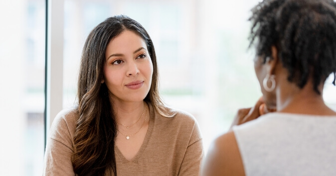 Two women talking in a meeting.