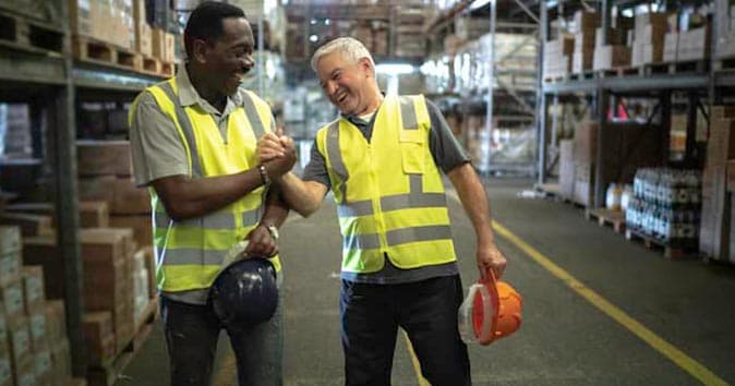 two males wearing vests and celebrating in the warehouse