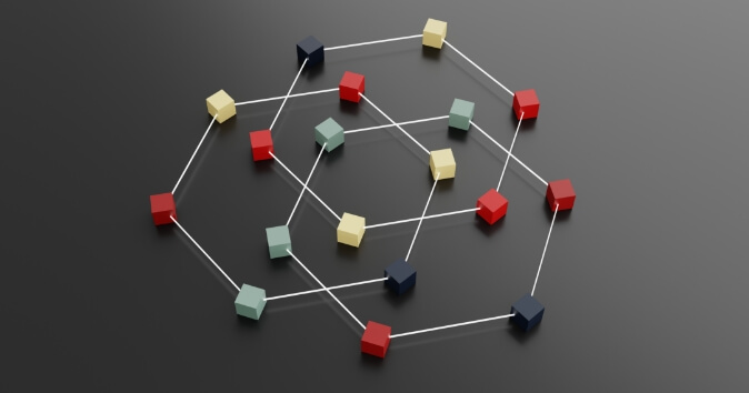 A collection of multicolored cubes is arranged in a network pattern on a dark surface, connected by thin lines. The cubes are in shades of red, green, yellow, and blue, and are positioned at various nodes of the network, creating a visually complex structure.