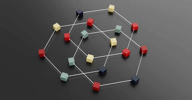 A collection of multicolored cubes is arranged in a network pattern on a dark surface, connected by thin lines. The cubes are in shades of red, green, yellow, and blue, and are positioned at various nodes of the network, creating a visually complex structure.