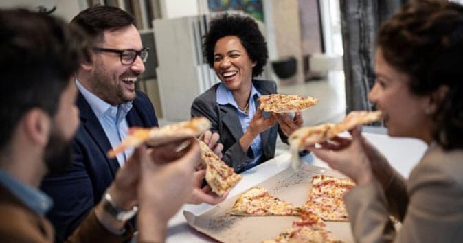 employee sitting around the table and having a pizza party