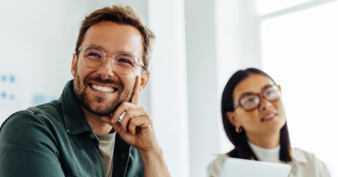 Man with glasses smiling off camera.