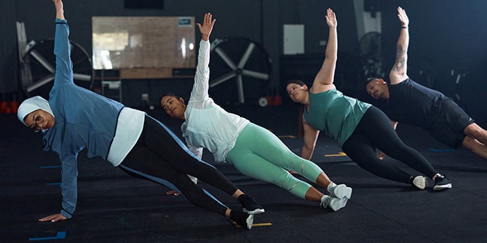 four people in a row doing side-planks during a workout