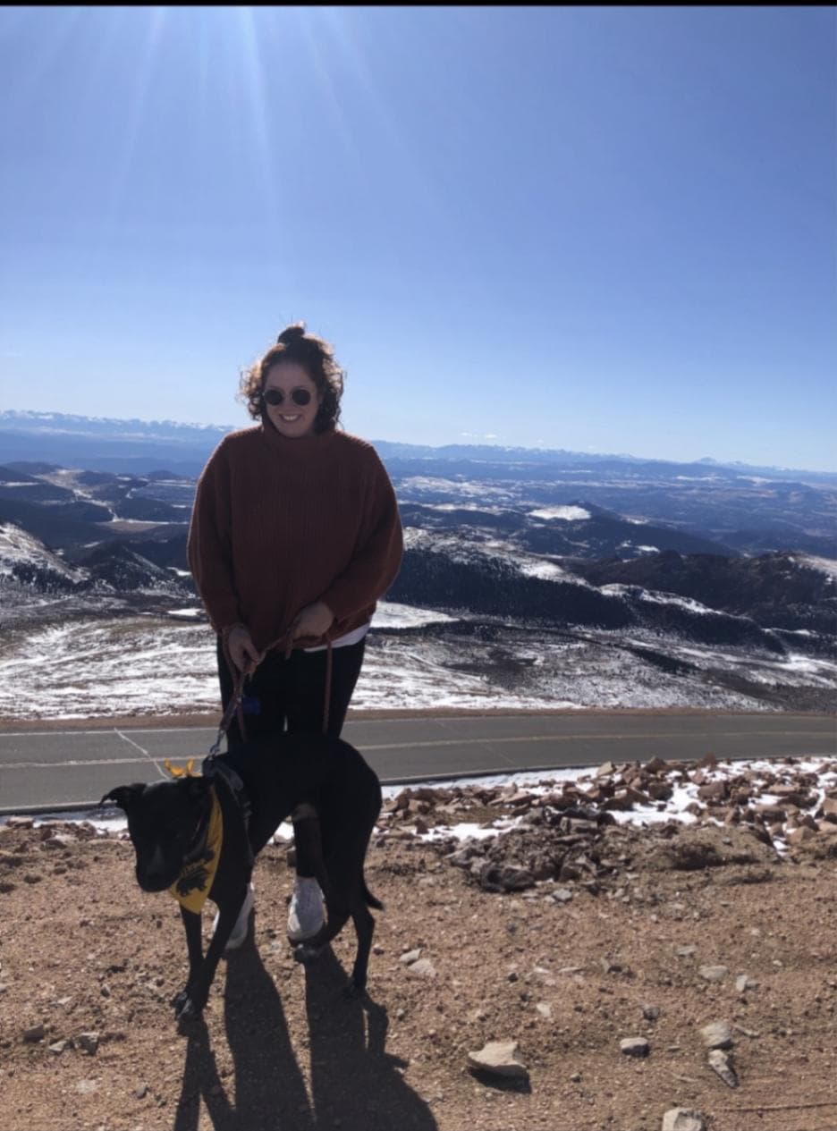 Kristin out walking with dog with mountains and snow behind her