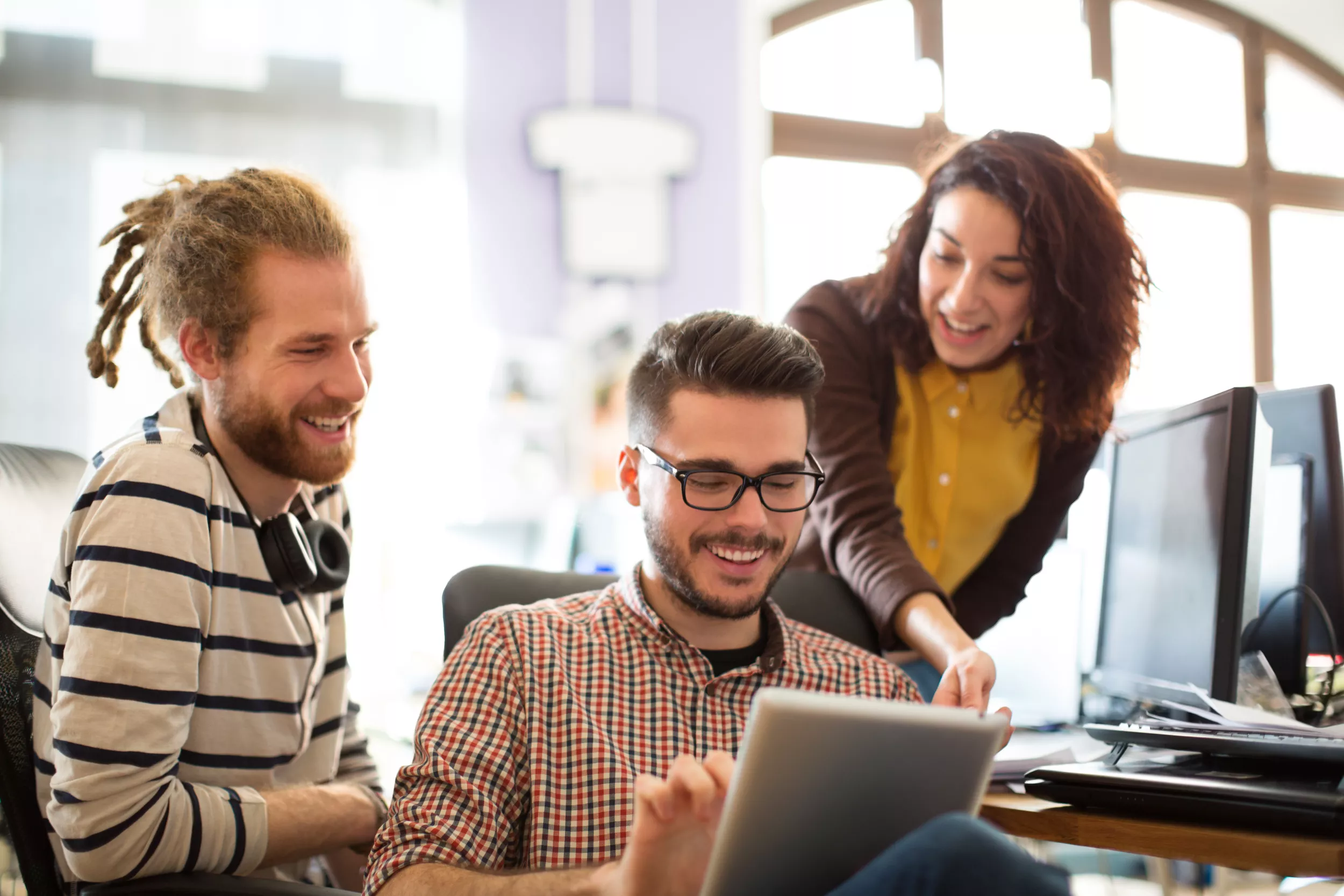 A group of three employees smile and talk about work