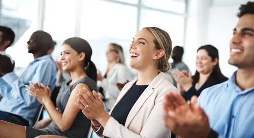 audience of people in business attire clapping