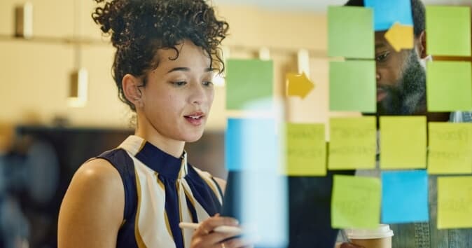 Woman planning with post-it notes on a glass wall.