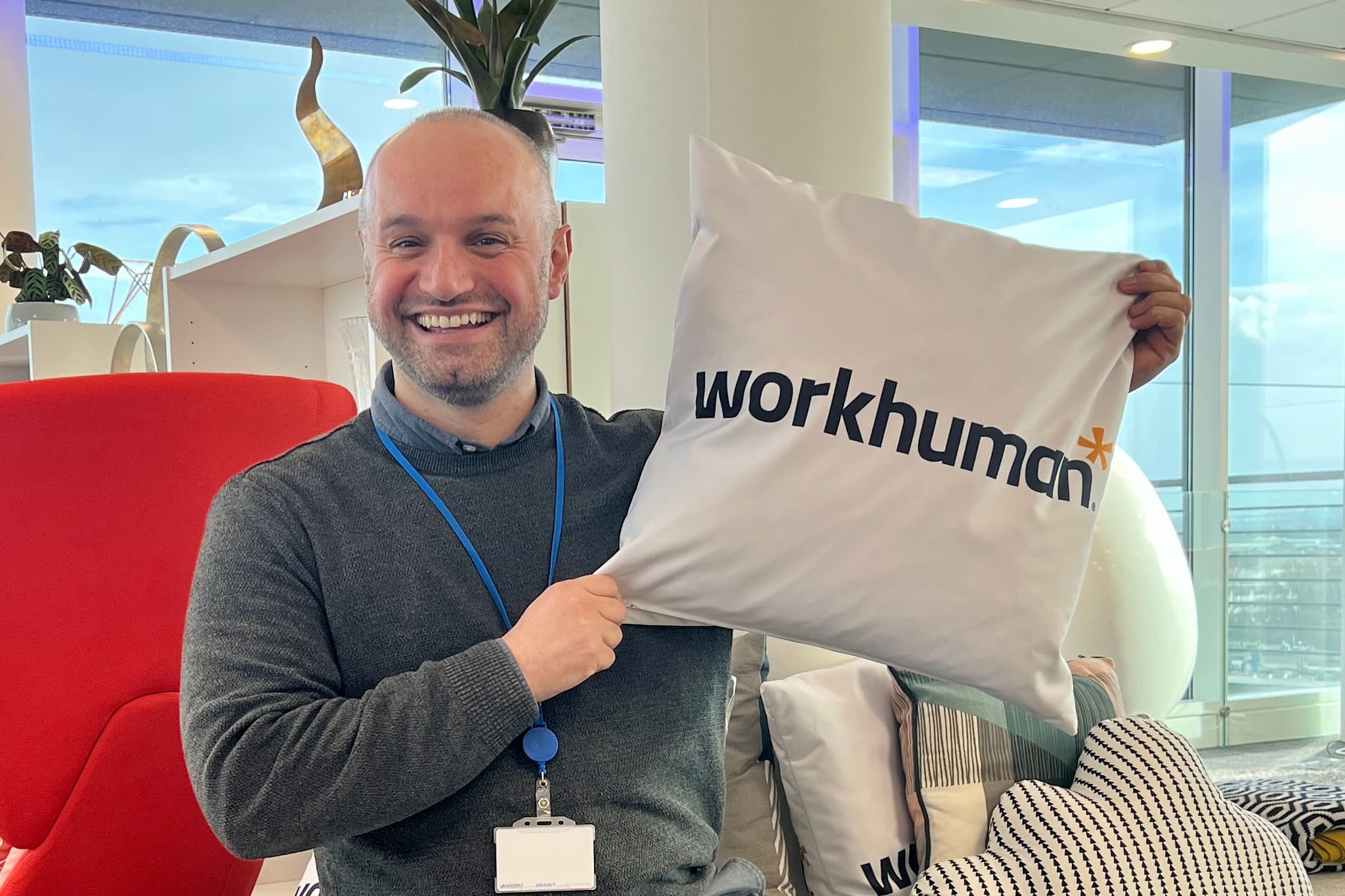 photo of Erhan Keskin holding a pillow printed with Workhuman's logo