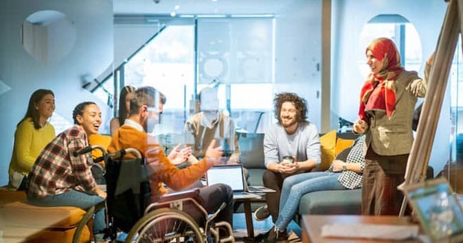 A group of employees sitting together and discussing and laughing.