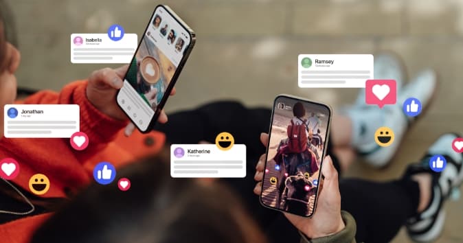 Two individuals are seated, each holding a smartphone. One screen displays a picture of a coffee drink, and the other shows a person riding a motorcycle, surrounded by reactions like hearts and thumbs-up icons in colorful overlays. Various names, including "Isabela," "Jonathan," "Ramsey," and "Katherine," appear as notifications above their corresponding reactions, suggesting interaction within a social media context. The setting conveys a casual, connected atmosphere.