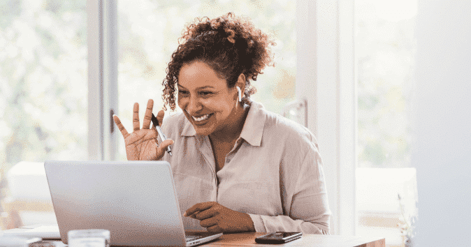 A smiling woman in a meeting with her remote team