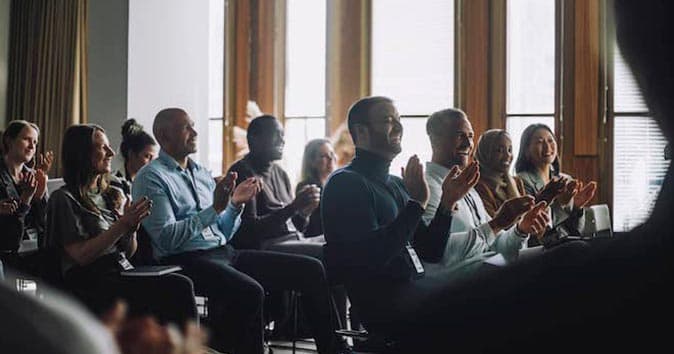 Group of people sitting on chairs and clapping