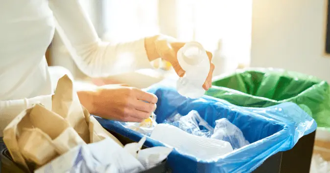 An employee in a green office segregating the waste in appropriate waste bins