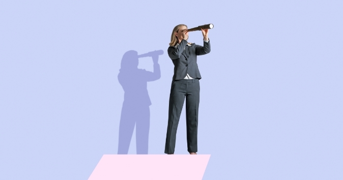 A businesswoman in a suit stands on a pink platform and looks through a telescope, gazing into the distance. Her shadow is visible on the background, which is a light blue color. The overall image conveys a sense of searching or looking ahead, possibly symbolizing vision or future planning.