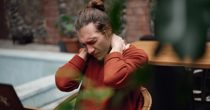man rubbing sore neck at desk