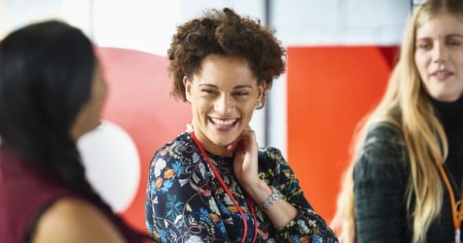 Three women in the frame, woman in middle is smiling.