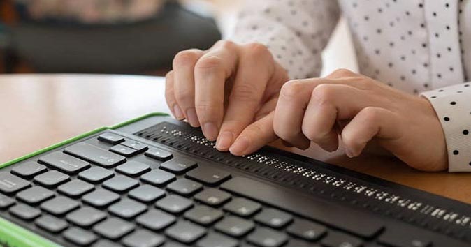 person typing using keyboard design for blind and visually impaired people