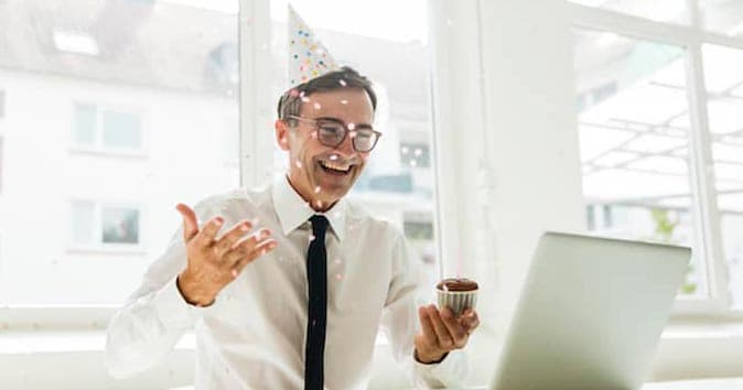 A man is holding a cupcake in his hand and smiling