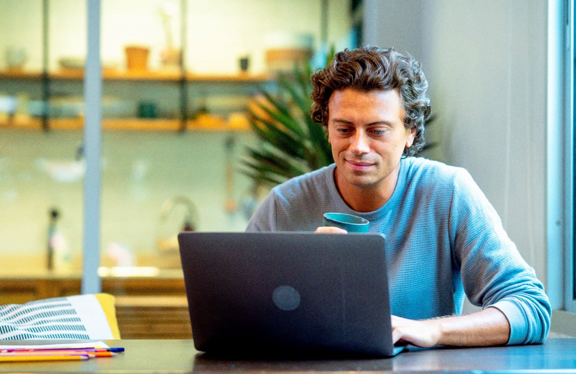 Individual looking at laptop drinking coffee