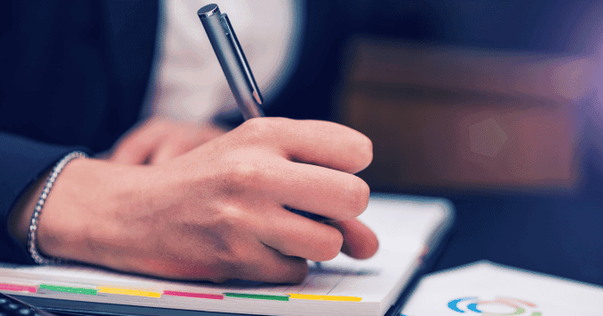 Close-up of a female employee write down notes in her agenda
