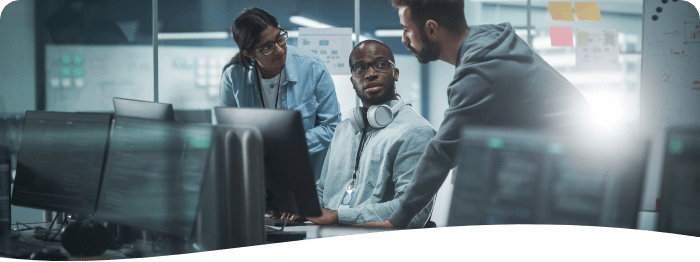 three employees gathered around a computer