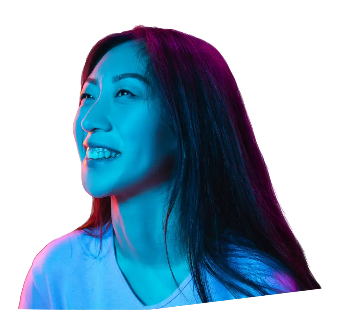 A woman smiling into a blue light.