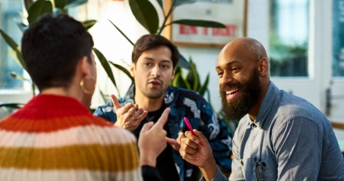 Three people talking while sitting.