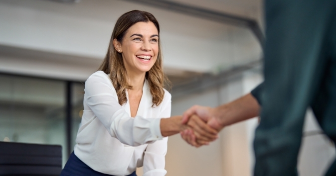 A woman and man shaking hands in and office.