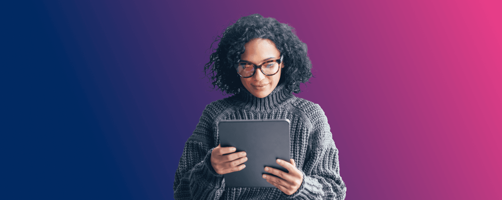 A woman with curly hair, wearing glasses and a cozy sweater, is focused on a tablet she is holding. The background features a gradient transitioning from blue to pink, creating a warm and inviting atmosphere.