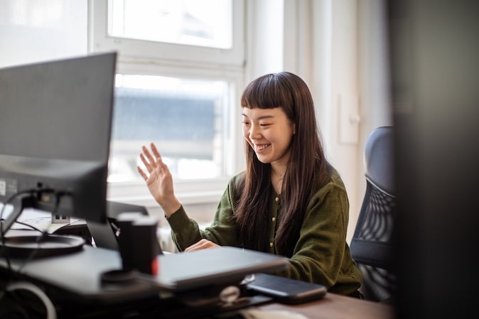 woman at her computer waving goodbye