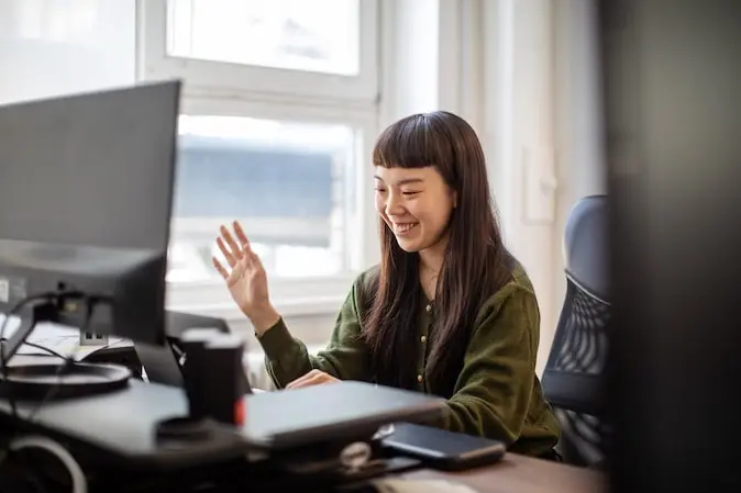 woman at her computer waving goodbye