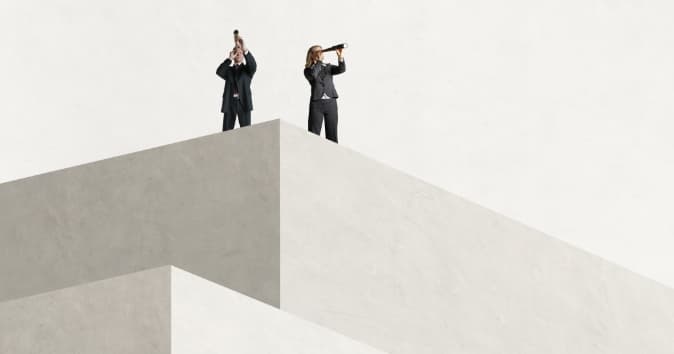 Two people looking through monocular telescopes from atop a wall.