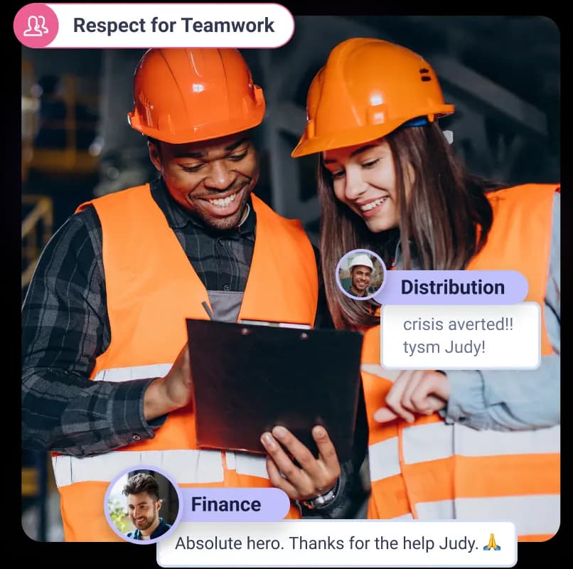 Two individuals wearing orange hard hats and safety vests are standing close together, looking at a clipboard. One person, on the left, has a broad smile and is wearing a checkered shirt, while the other, on the right, has long brown hair and is wearing a light blue shirt. They appear to be engaged in a discussion about the clipboard's contents in a work environment.