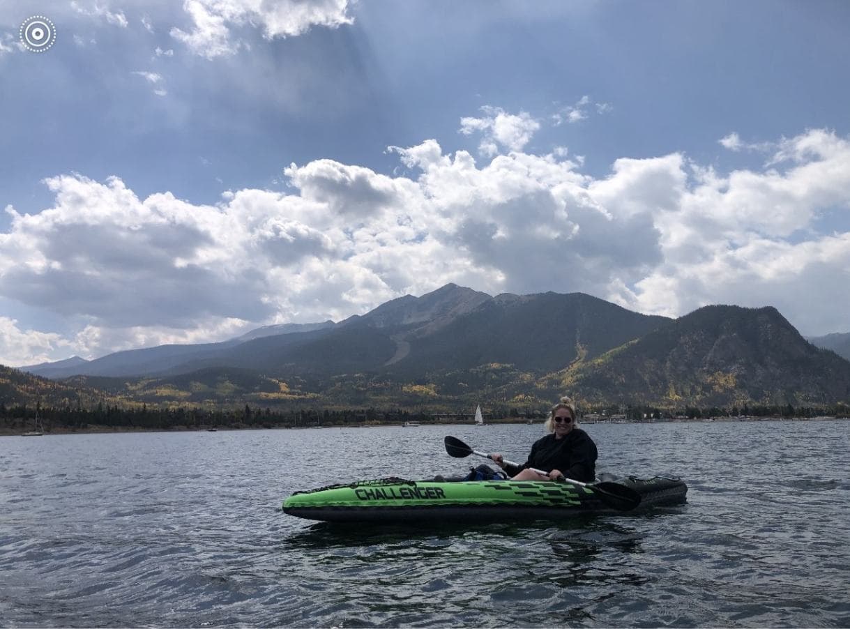 Ashley in a canoe in a lake with mountains behind her