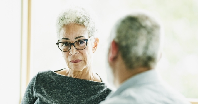 Two people talking with a woman looking toward the camera.