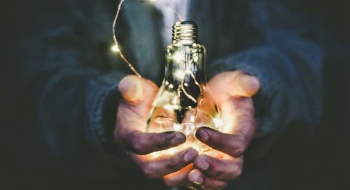 man holding a glowing lightbulb symbolizing the power of leadership feedback