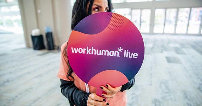 woman holding a fan with the words "workhuman live" written on it